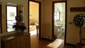 Una camera d'hotel con un comò in legno, uno specchio, una pianta in vaso e vista sul bagno.