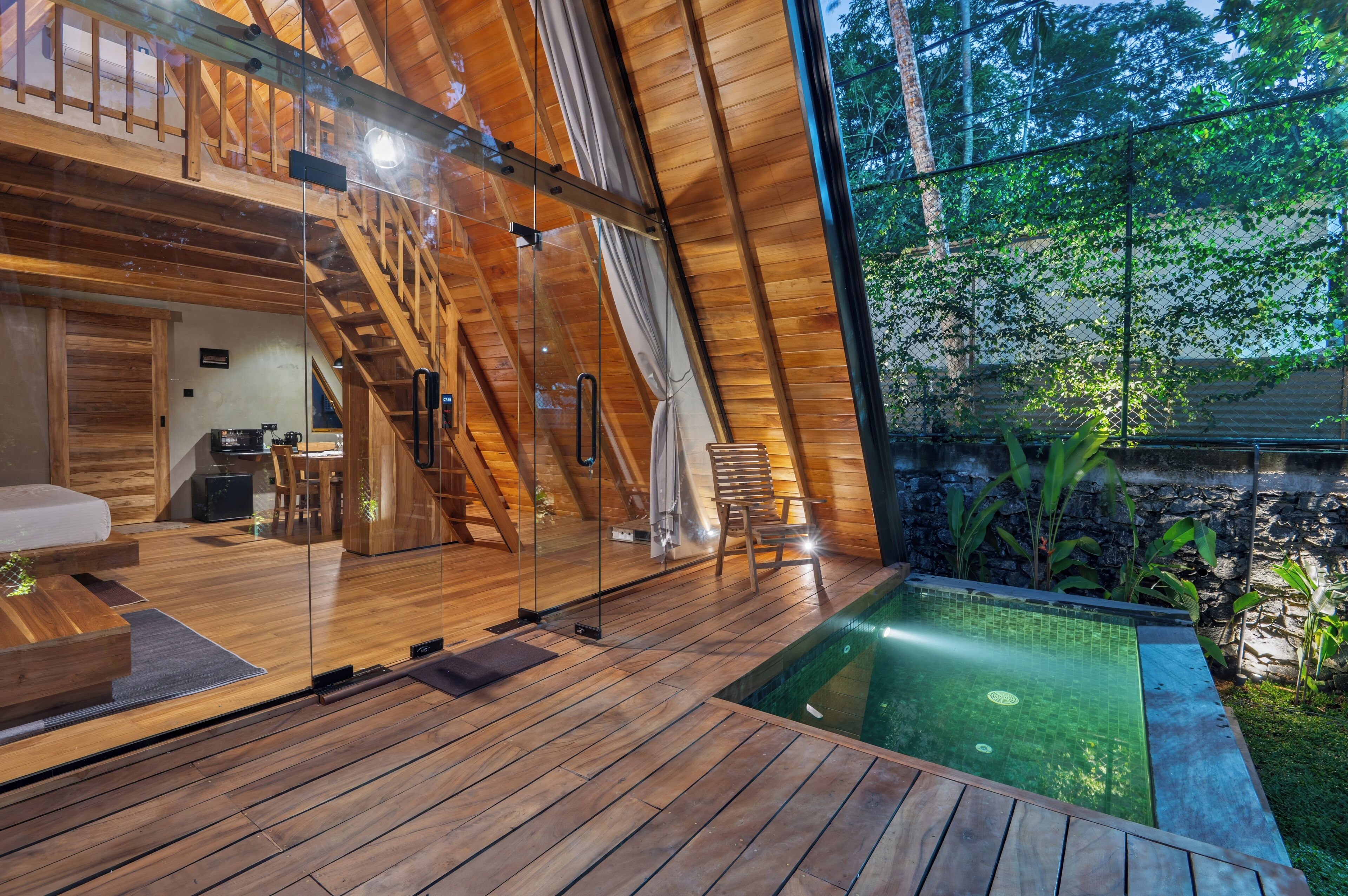 A wooden interior with a glass wall, a pool, and a staircase.