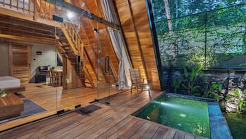 A wooden interior with a glass wall, a pool, and a staircase.