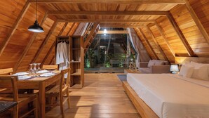 An attic-style room with a wooden ceiling, a bed, a desk with chairs, and a dining table. - Ceylon Canopy (Dickwella)