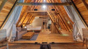 A wooden interior with a loft bed, sofa, and coffee table. - Ceylon Canopy (Dickwella)