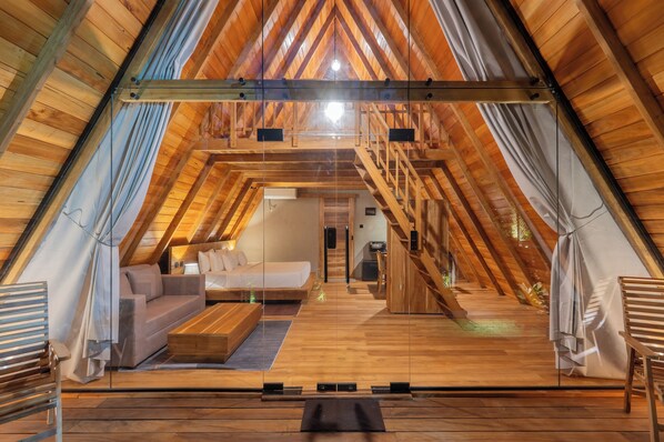 Un interior de madera con una cama en altillo, sofá y mesa de centro.