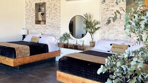 Una habitación con dos camas, una pared de ladrillo, techo de madera y un espejo.
