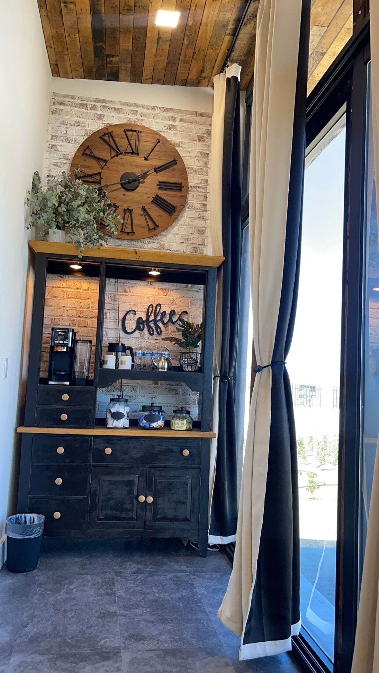 Una habitación con un gran reloj de madera, una zona para café y vistas a través de una ventana.