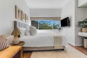 A bedroom with a bed, bedside table, lamp, and a TV. - Ashry Collective-Ocean & Mountain Views (Cape Town)