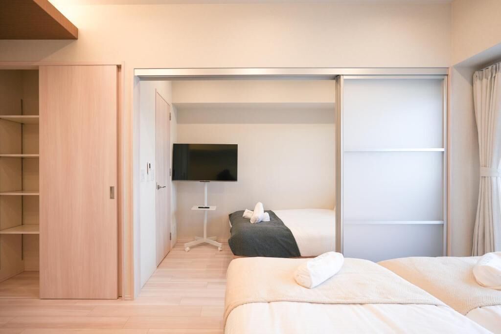 A bedroom with two beds, a TV, and a wardrobe.