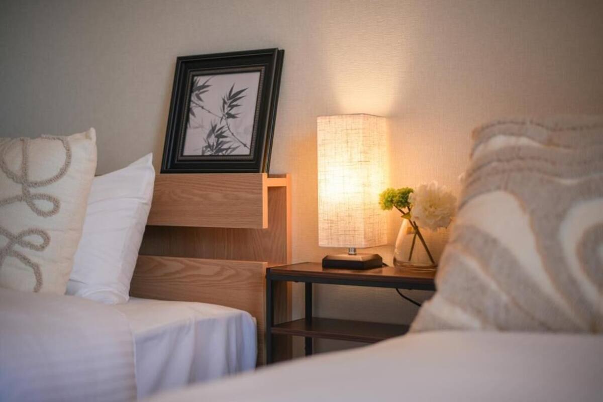 Une chambre d’hôtel avec deux lits, une table de chevet avec une lampe et un tableau encadré au mur.