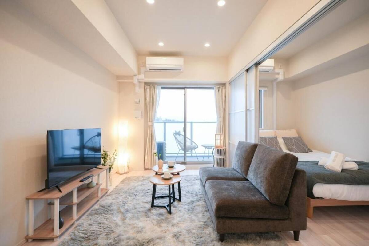 Un salon moderne doté d’un téléviseur à écran plat, d’un canapé, d’une table basse et d’une grande fenêtre offrant une vue dégagée.