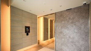 A modern hallway with a glass partition, a digital keycard reader, and a sliding door. - AYA RESIDENCE (Osaka)
