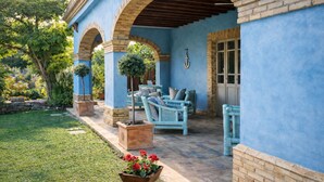 A covered patio with blue walls, brick arches, and outdoor furniture.