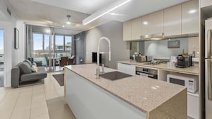 A modern kitchen with a central island, stainless steel appliances, and a view to the outside. - Hamilton Riverview Apt | Balcony & Pool (Hamilton)