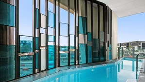 A swimming pool with a modern design, surrounded by large windows and a view of the cityscape. - Hamilton Riverview Apt | Balcony & Pool (Hamilton)
