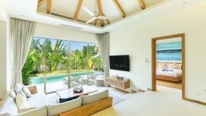 Una sala de estar moderna con un amplio ventanal, un televisor de pantalla plana y vista a la piscina.