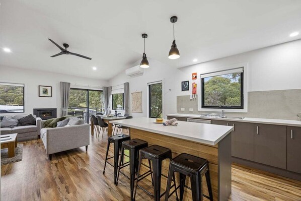 A modern kitchen with a large island, bar stools, and a ceiling fan.