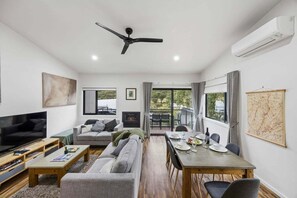 A modern living room with a sofa, TV, dining table, and a fireplace.
