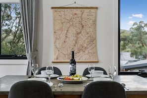 A dining table with plates, glasses, and a bottle of wine, set against a wall with a map.