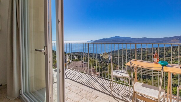 A balcony with a clear view of the sea and mountains, a table with a bottle, and a chair. - Residenza Bellavista - Bianco (Capoliveri)