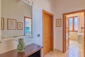 A hallway with a wooden door, a mirror, and a fish-shaped vase on a console table. - Residenza Bellavista - Bianco (Capoliveri)