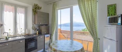 Une cuisine avec une table et des chaises, une vue sur la mer et un balcon.