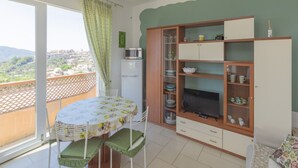 Varanda com mesa e cadeiras, um rack de TV com armários e vista para o horizonte urbano.