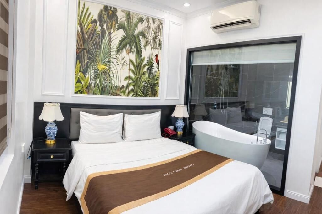 A hotel room with a bed, nightstands, a large painting, a bathtub, and a window.