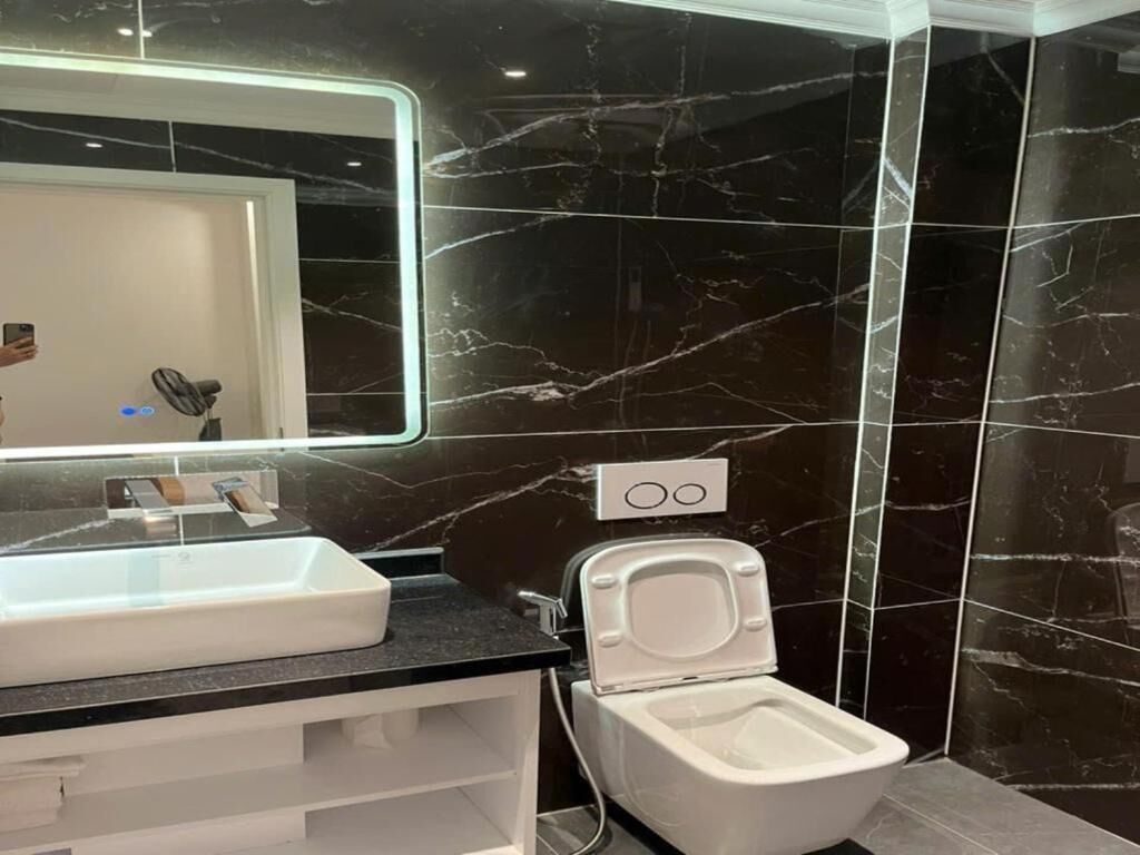 A modern bathroom with a white sink, a mirror, and a toilet.