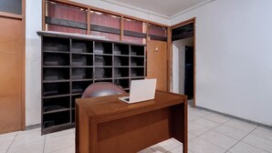 Una habitación con un escritorio de madera, una computadora portátil y un estante grande con varios compartimentos.