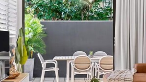 A modern living room with a sofa, a coffee table, and a dining area with chairs and a table. - Haven at Hastings (Tweed)