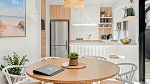 A modern kitchen with a central island, white cabinetry, and a hanging light fixture. - Haven at Hastings (Tweed)