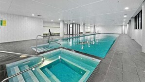 A swimming pool with multiple lanes, a changing room area, and a reception desk. - New 2 bedroom apartment. Garden view with pool, jacuzzi,sauna & gym. (Eastgardens)