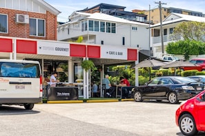 A cafe with outdoor seating, a Tim Adams specialty coffee sign, and a parked van.