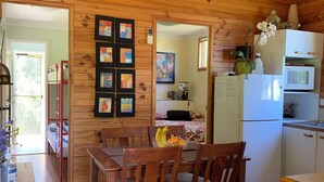 Un interno in legno con zona pranzo, angolo cottura e un letto con vista.