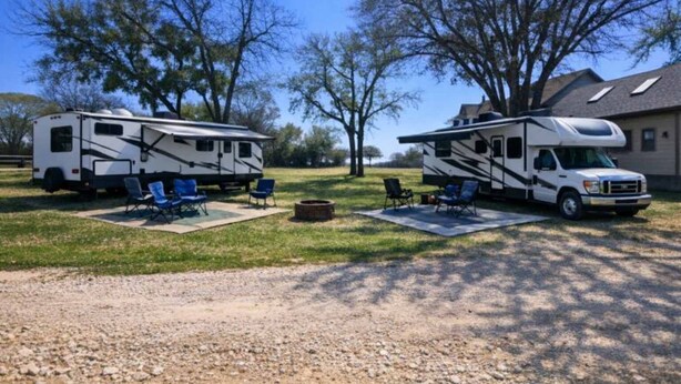 Parco per veicoli ricreativi con camper, sedute all'aperto e terreno sterrato.