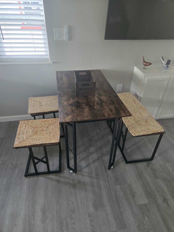 A rectangular dining table with four woven chairs, a dark wooden finish, and black metal legs.