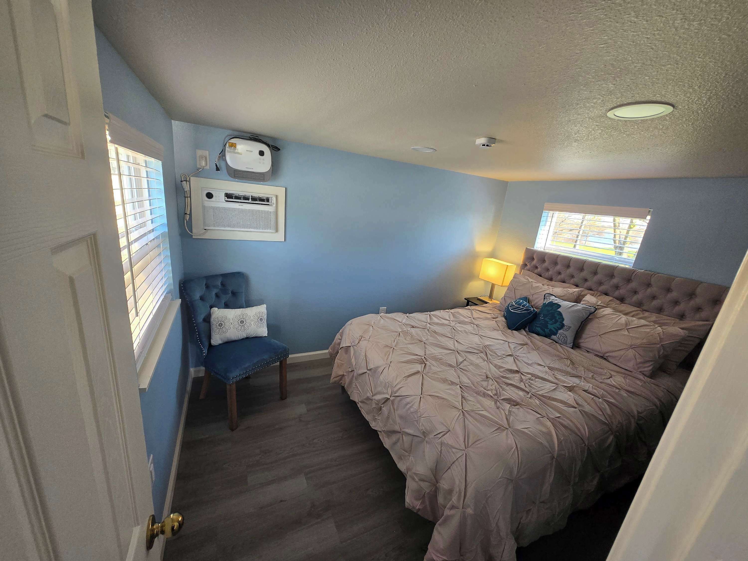 Ein Schlafzimmer mit einem Bett, einem Sessel, einer Lampe und einem Deckenventilator.