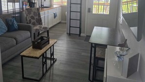 Ein kompakter Wohnraum mit Schlafgalerie, einer Küchenzeile, einem Essbereich und einer Sitzecke inklusive Sofa und Couchtisch.