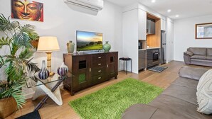 Uma sala de estar moderna com televisão de tela plana, sofá, área de jantar e cozinha.