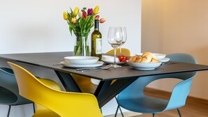 A dining table with a bottle of wine, two glasses, a bowl of cherries, a plate of croissants, and a vase of tulips. - Stylish holiday apartment in Jenbach centre (Jenbach)