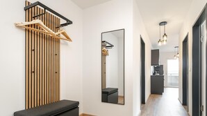 A modern hallway with a bench, a wooden slat wall, a mirror, and a kitchen area visible through an open door. - Stylish holiday apartment in Jenbach centre (Jenbach)