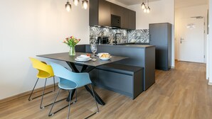 Una cucina moderna con isola centrale, due sedie, un vaso di fiori e un tavolo da pranzo per due persone.