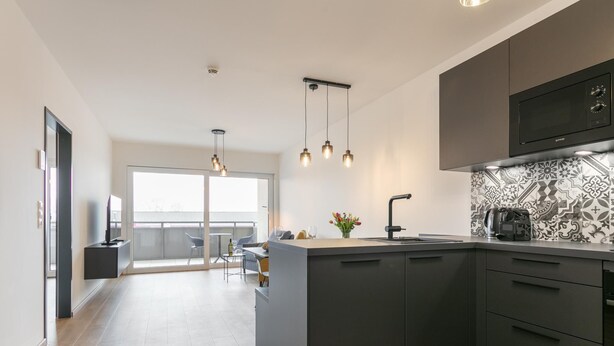 Una cucina moderna con isola centrale, mobili neri e piastrelle decorate.