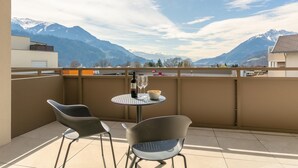 Un balcone con un tavolo, due sedie, una bottiglia di vino e una ciotola di snack.
