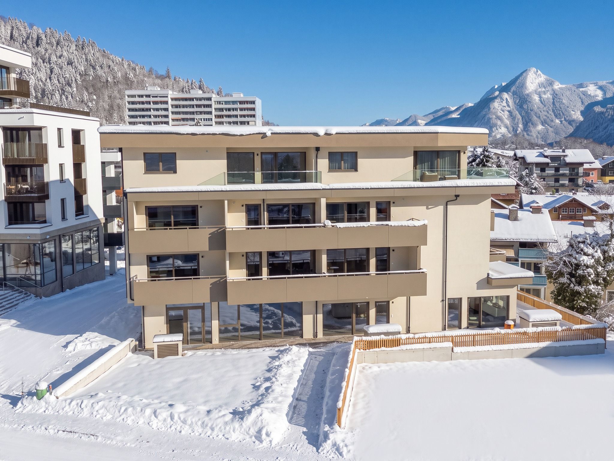 Un hôtel à plusieurs étages doté de balcons, un paysage enneigé et des montagnes en arrière-plan.