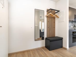 Un interior moderno con un panel de madera en la pared, un banco negro y una zona de cocina con un salpicadero estampado.