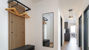 Een moderne hal met een bank, wand van houten latten, spiegel en hanglampen.