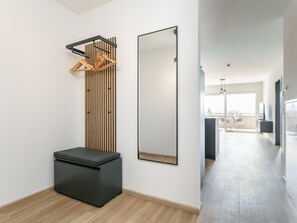 A modern interior with a bench, a vertical wooden panel, and a large mirror.