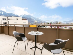 A balcony with two chairs and a table, overlooking a cityscape and mountains. - Modern apartment with terrace in Jenbach (Jenbach)