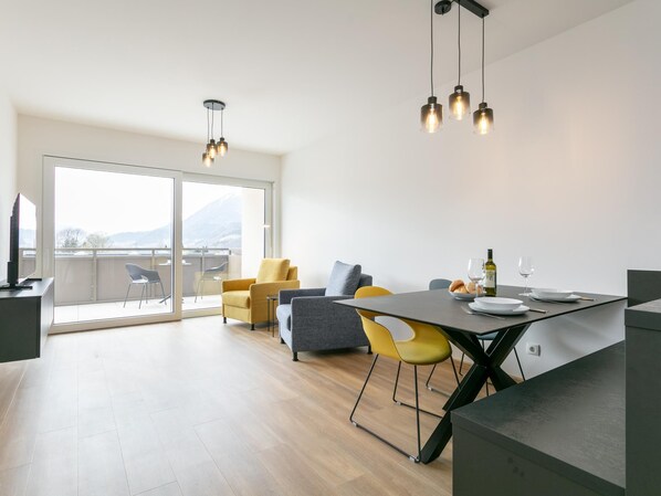 A modern living space with a dining area, a sofa, and a balcony with a view. - Modern apartment with terrace in Jenbach (Jenbach)