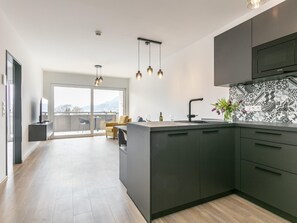 Een moderne keuken met een groot eiland, donkere kastjes en een behangetje met patroon.