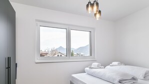 Un dormitorio con una cama, una ventana y una lámpara colgante.